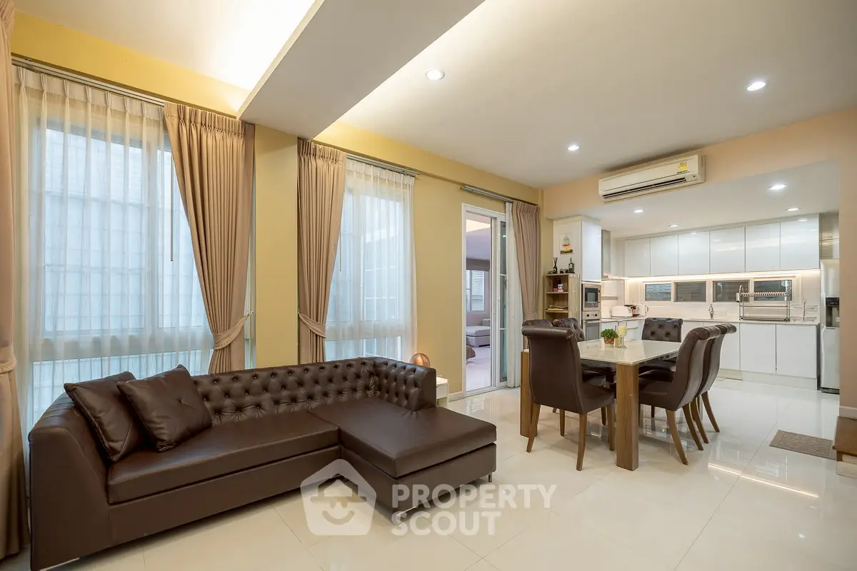 Spacious open-plan living room with elegant furniture and modern kitchen in a luxurious home.