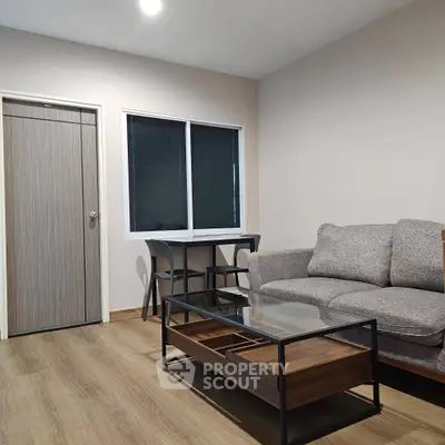Modern living room with cozy sofa and glass coffee table, featuring sleek wooden flooring and minimalist decor.
