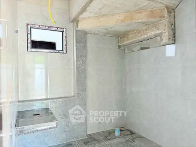 Under-construction bathroom with tiled walls and floor, featuring a shower area.