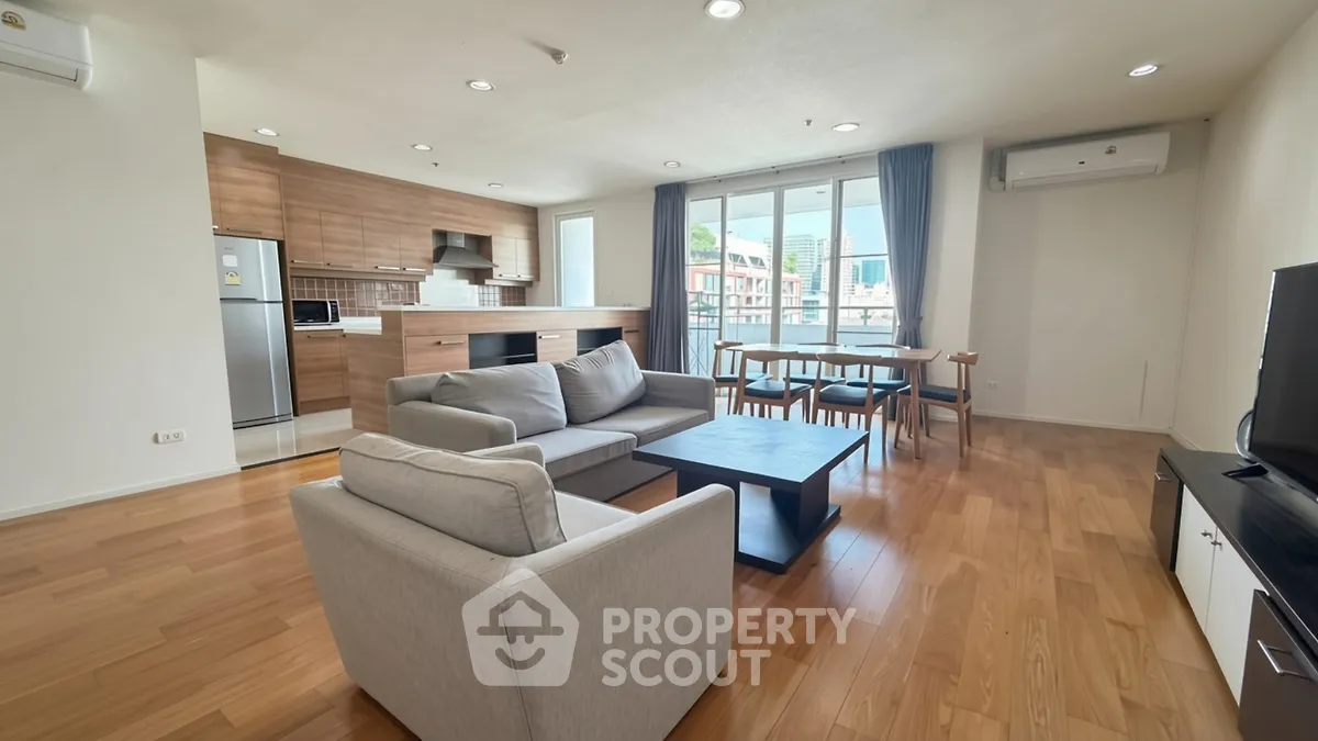 Spacious modern living room with open kitchen and city view, featuring hardwood floors and stylish furniture.