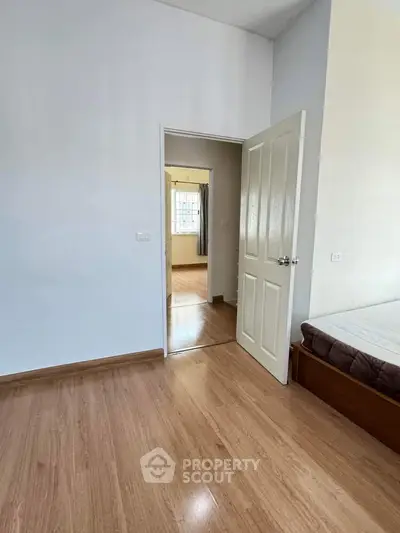 Spacious bedroom with wooden flooring and open door to adjacent room