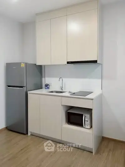 Modern compact kitchen with sleek cabinetry and built-in appliances in a stylish apartment.