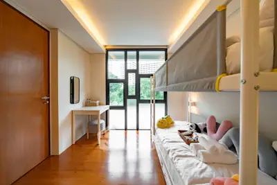 Modern bedroom with bunk beds and natural light, featuring a cozy workspace and wooden flooring.