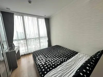 Modern bedroom with large windows and stylish decor in a high-rise apartment.