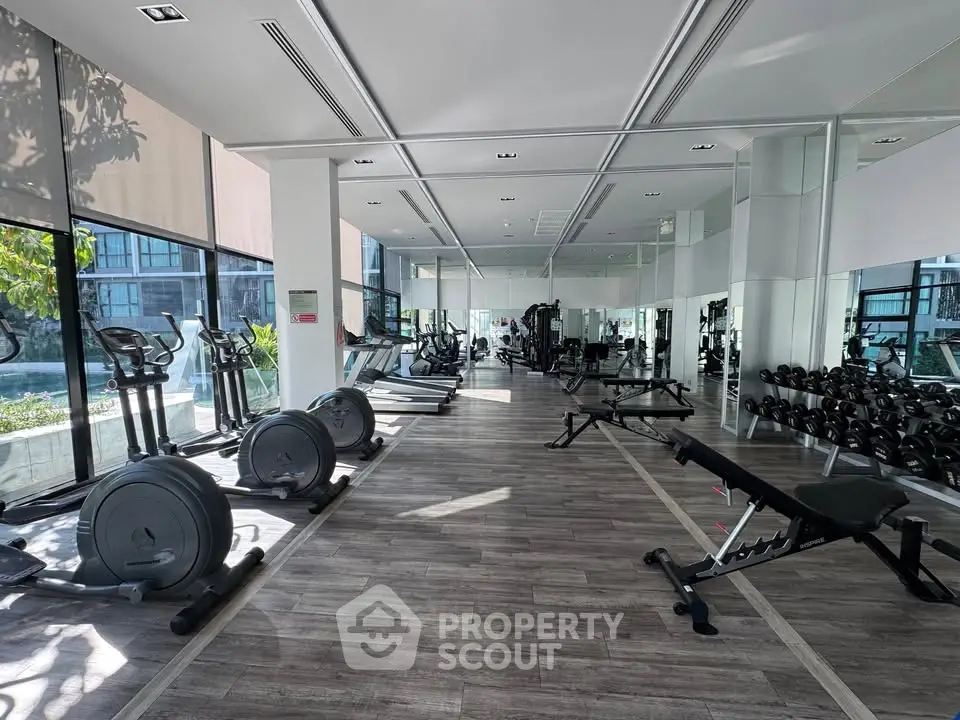 Spacious modern gym with state-of-the-art equipment and large windows offering natural light.