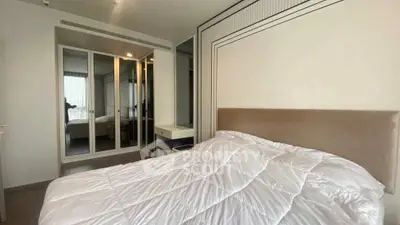 Modern bedroom with mirrored closet and cozy bedding in a stylish apartment.