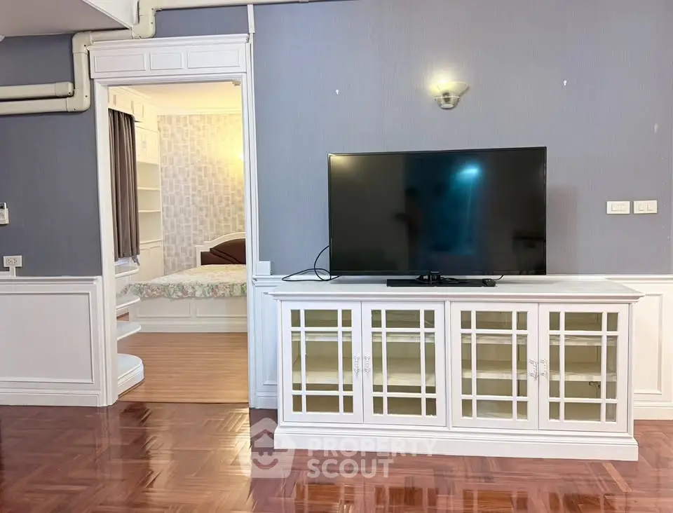 Spacious living room with elegant TV cabinet and glimpse of cozy bedroom