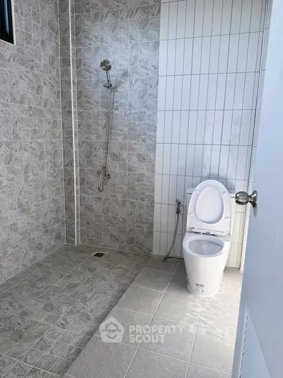 Modern bathroom with tiled shower and toilet in a sleek design.