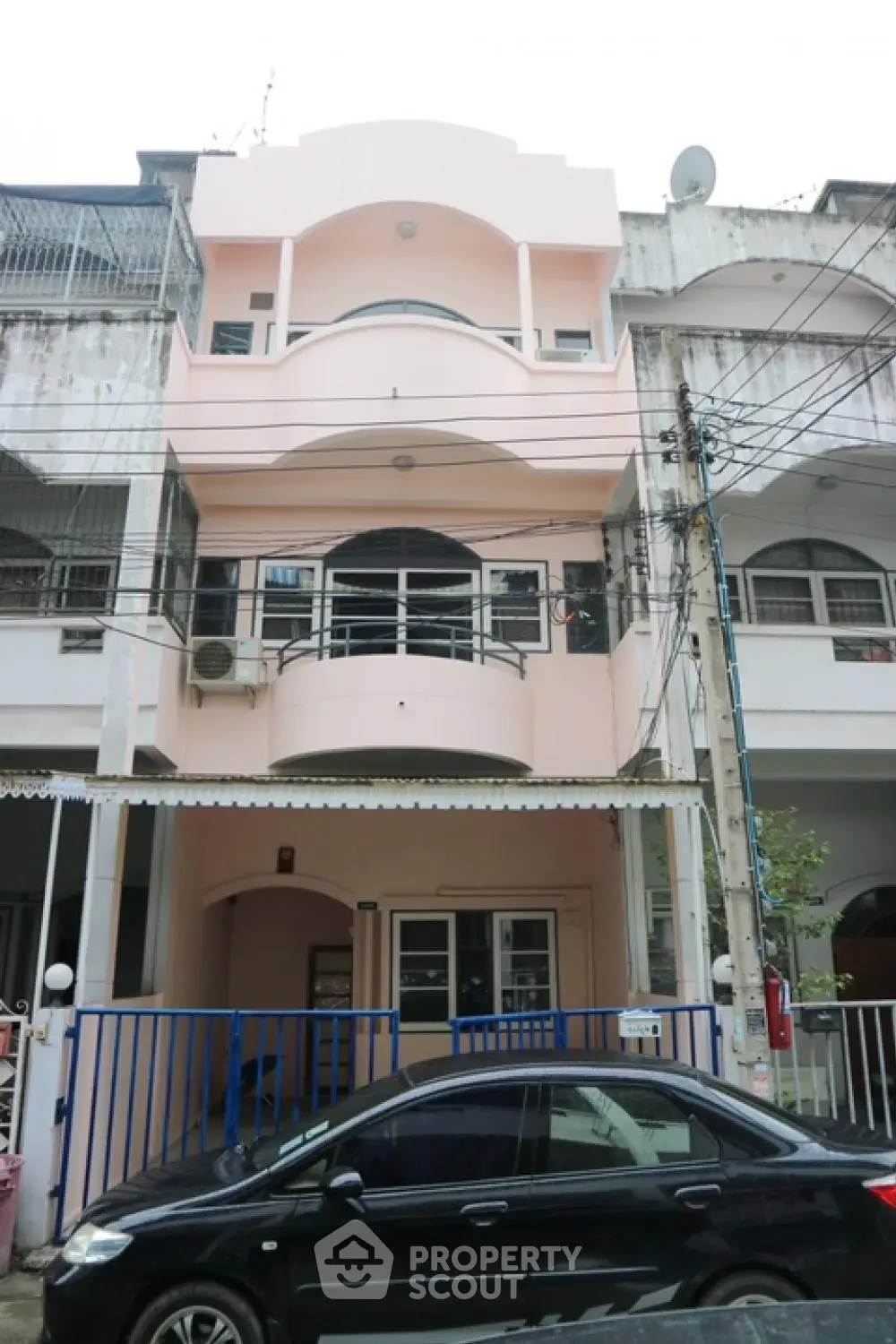Charming three-story townhouse with balcony and gated entrance in urban setting