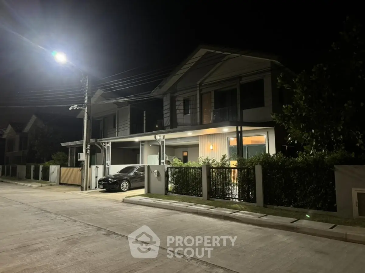 Modern two-story house with driveway and night lighting in a serene neighborhood.