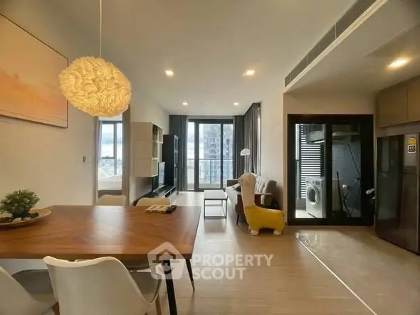 Modern open-plan living room with stylish dining area and large windows.