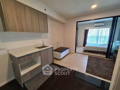 Modern open-plan kitchen and living area with sleek cabinetry and cozy bedroom view.