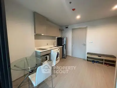 Modern compact kitchen with dining area and appliances in a cozy apartment.