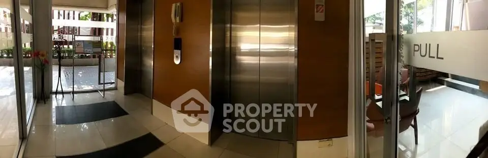 Modern building entrance with sleek elevator and glass doors