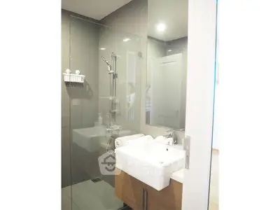 Modern bathroom with glass shower and sleek vanity in contemporary home.