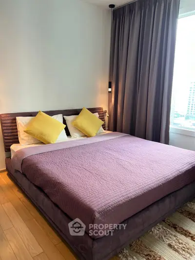 Spacious bedroom with modern decor and large window offering city views.