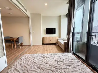 Modern bedroom with balcony view and cozy seating area in a stylish apartment.
