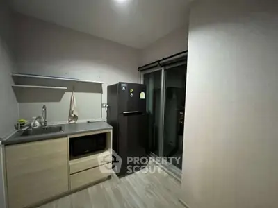 Modern kitchen with sleek black fridge and compact design, perfect for urban living.