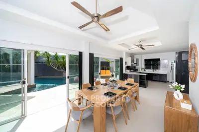 Spacious open-plan living area with modern kitchen, large dining table, and seamless indoor-outdoor flow to a private pool area, perfect for entertaining.