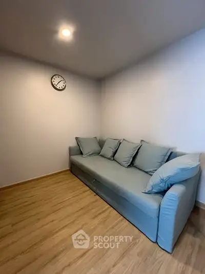 Cozy small living room with modern blue sofa and wall clock, perfect for relaxation.