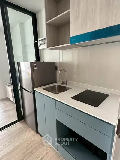 Modern compact kitchen with sleek cabinetry and stainless steel appliances in a stylish apartment.