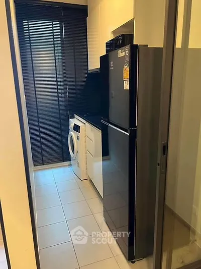 Modern kitchen with sleek appliances and washing machine in compact layout.