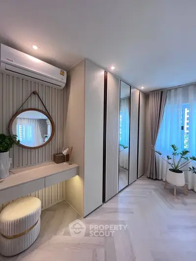 Stylish bedroom with modern decor, mirrored wardrobe, and natural light.