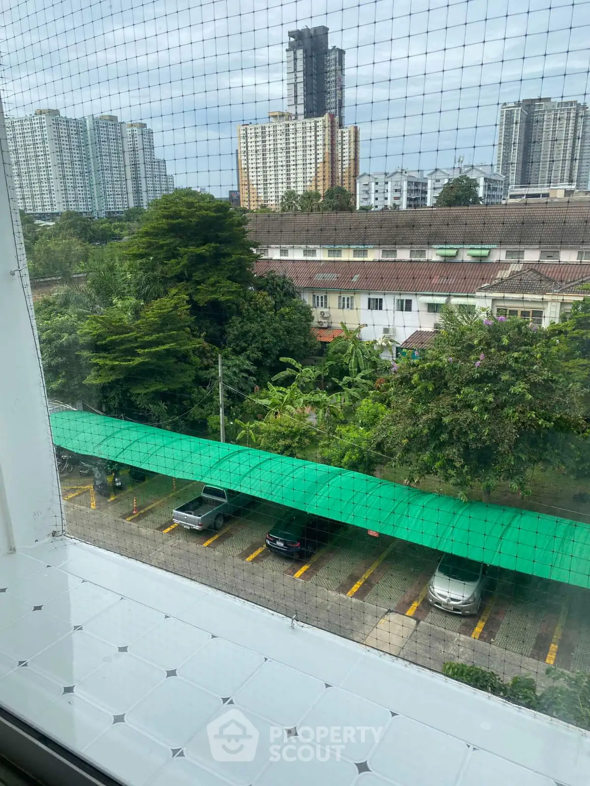 Scenic urban view from a window overlooking lush greenery and city buildings.