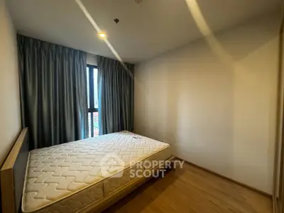 Spacious bedroom with large window and wooden flooring in modern apartment