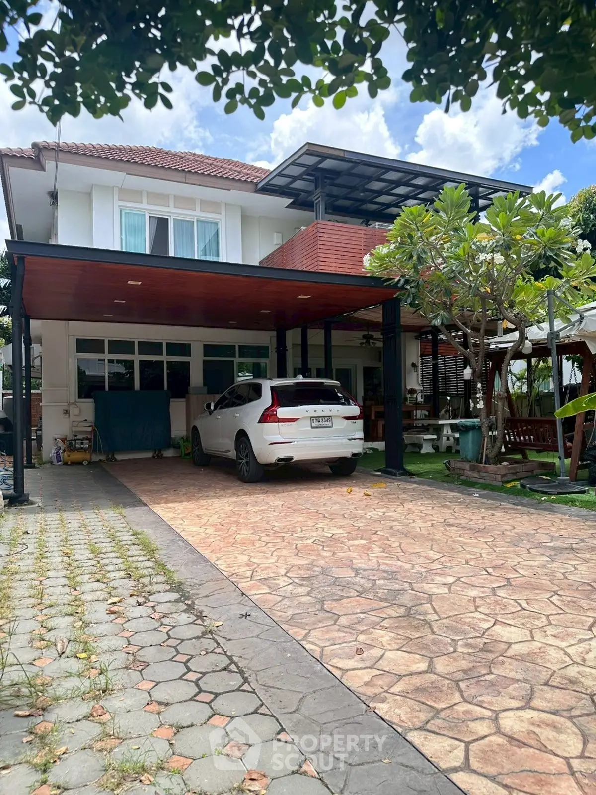 Charming two-story house with carport and lush garden, perfect for family living.