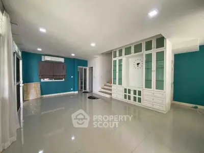 Spacious living room with modern built-in shelving and vibrant teal walls