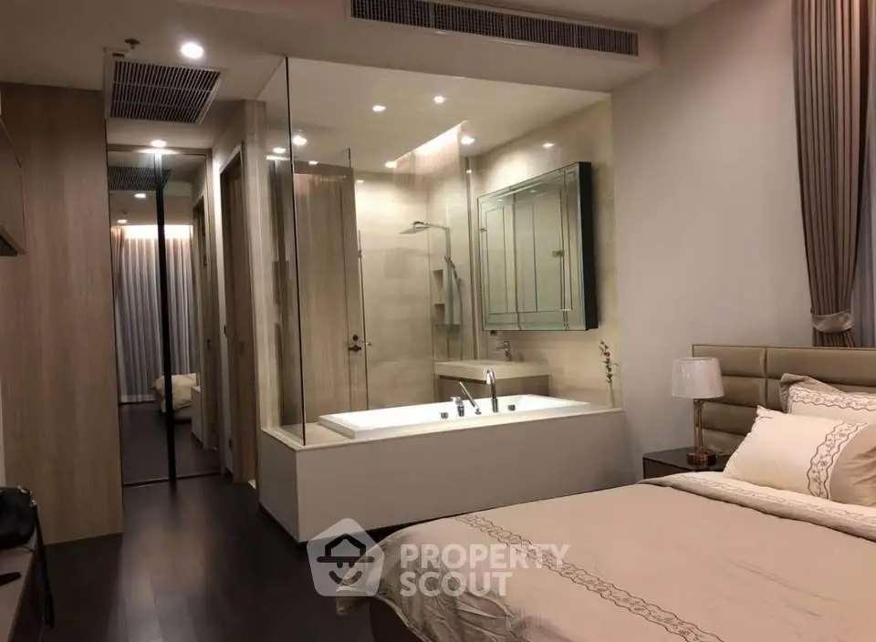Luxurious bedroom with ensuite glass-walled bathroom featuring a modern bathtub.