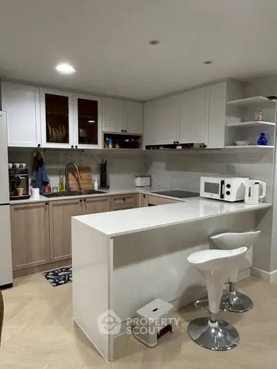 Modern kitchen with sleek design, featuring white cabinets, island, and contemporary bar stools.