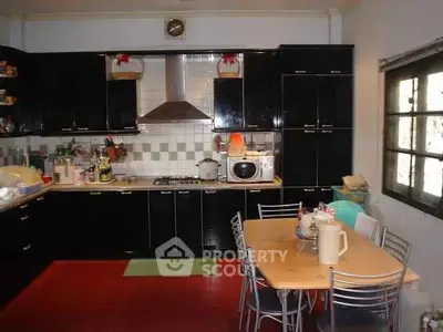 Spacious kitchen with black cabinets and dining area, featuring modern appliances and ample storage.