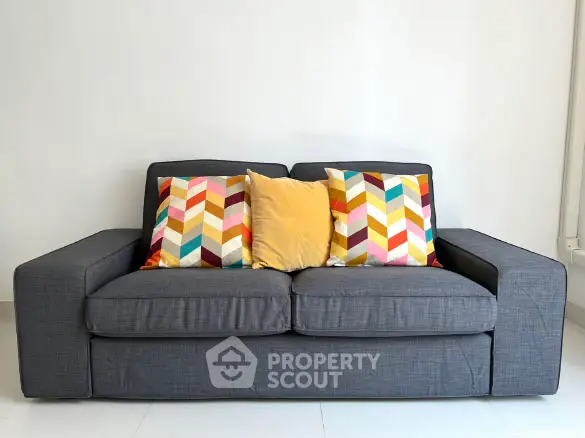 Stylish gray sofa with colorful chevron pillows in modern living room.