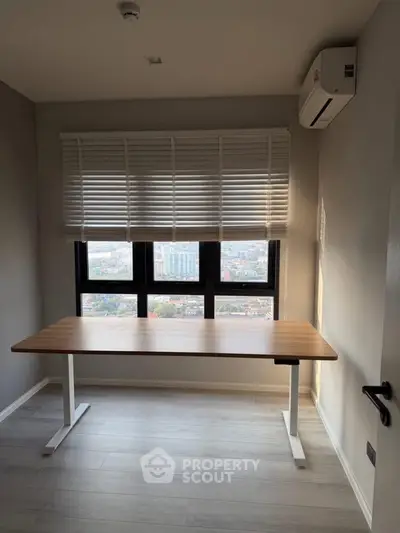 Modern study room with large window and adjustable desk, offering a stunning city view.