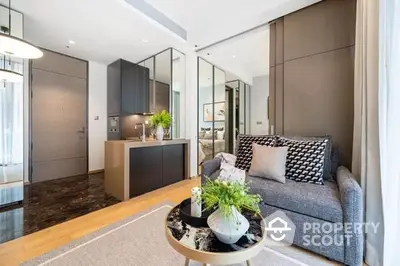 Modern apartment with an open layout connecting a cozy living room to a sleek kitchen, featuring elegant furnishings and tasteful decor.