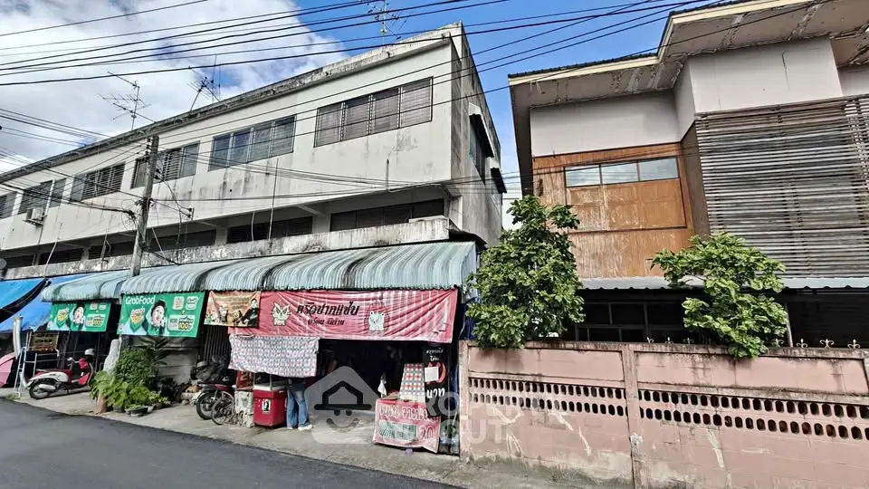 Street view of commercial buildings with shops and residential units, showcasing urban architecture.