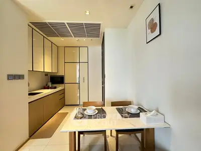 Modern kitchen with dining area, sleek cabinetry, and elegant table setting in a contemporary apartment.