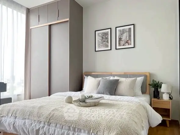 Modern bedroom with cozy decor and large wardrobe in stylish apartment.