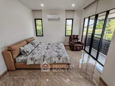 Spacious bedroom with large windows and modern furnishings, offering a serene view.