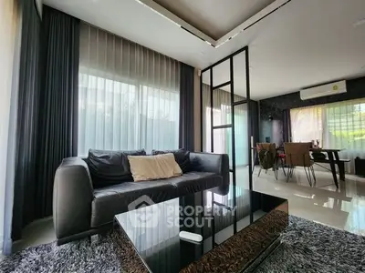 Modern living room with sleek black sofa and stylish dining area, featuring large windows and elegant decor.