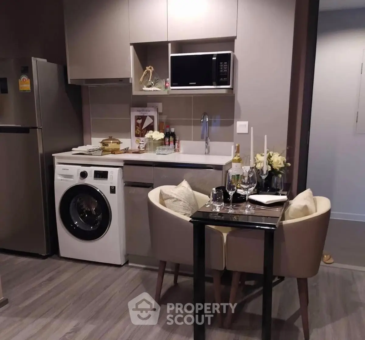 Modern kitchen with washing machine, microwave, and cozy dining area.