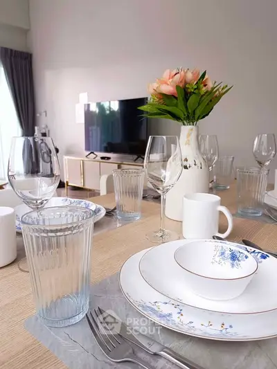 Elegant dining setup in modern living room with TV and floral centerpiece.