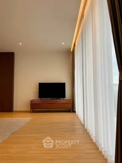Spacious modern living room with large windows and wooden flooring