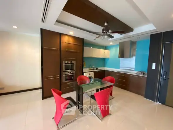 Modern kitchen with red chairs, sleek cabinetry, and stainless steel appliances.
