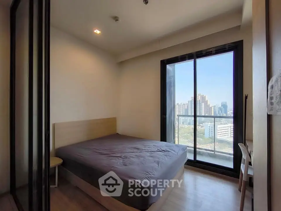 Modern bedroom with city view and large window in high-rise apartment