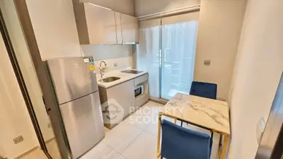 Modern compact kitchen with dining area and balcony access in stylish apartment.
