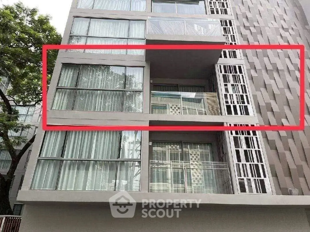 Modern apartment building with large windows and balconies in urban setting.