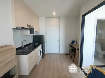 Modern studio apartment with sleek kitchenette featuring built-in appliances and ample natural light, perfect for urban living.